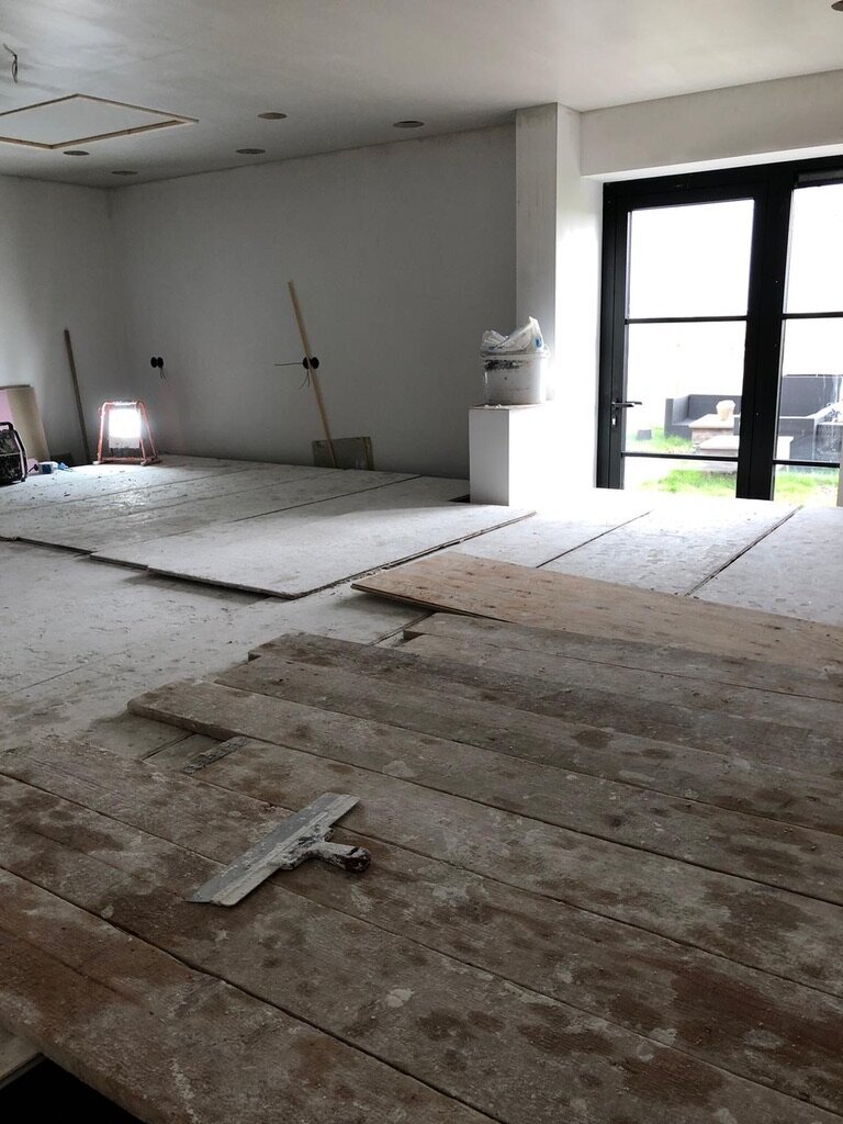 De ruimte tijdens het werk, met afgedekte vloer en grote pui