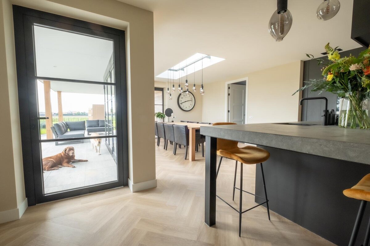 Strak afgewerkte woonkamer met keuken na stucwerk door Ad Schaap Stukadoorsbedrijf
